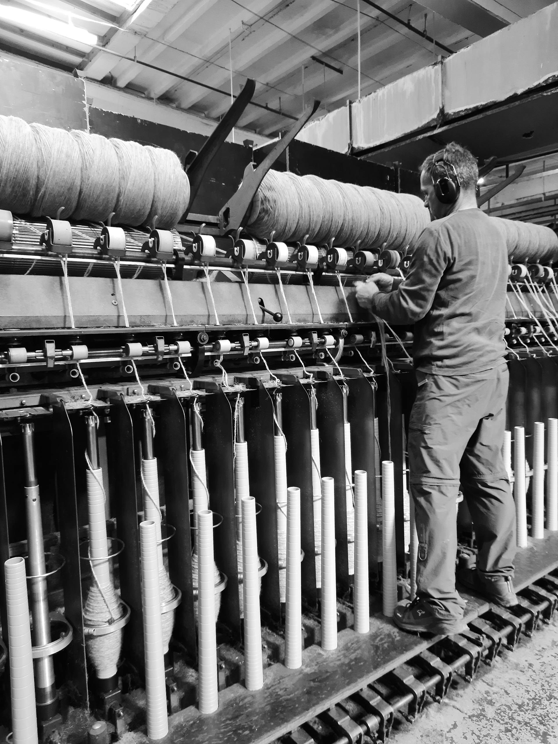A man working with industrial machinery in a factory setting. Black and white image.